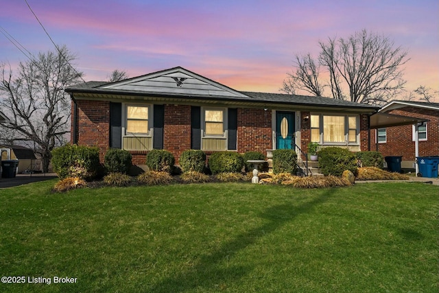 view of front of house featuring an attached carport, a front lawn, and brick siding