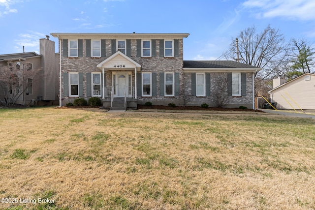 colonial inspired home with a front yard and brick siding