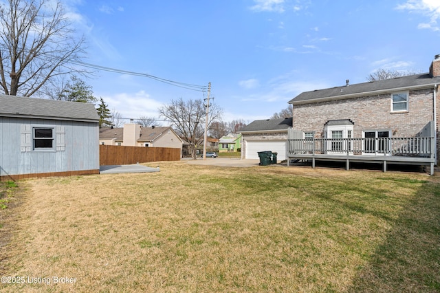 view of yard featuring a deck, fence, and a garage