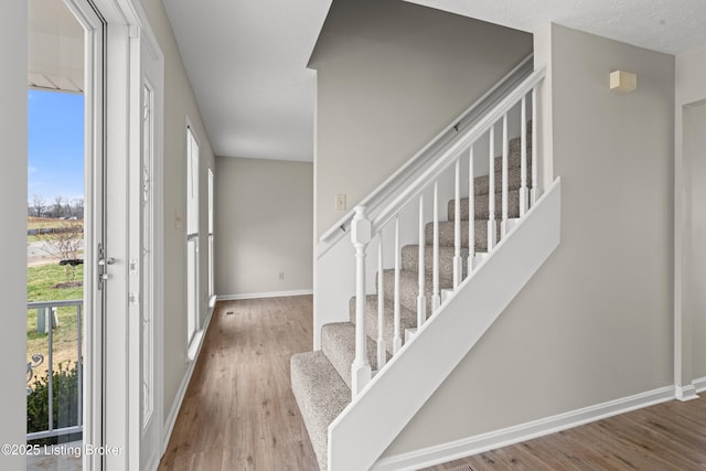 foyer featuring stairway, a textured ceiling, baseboards, and wood finished floors