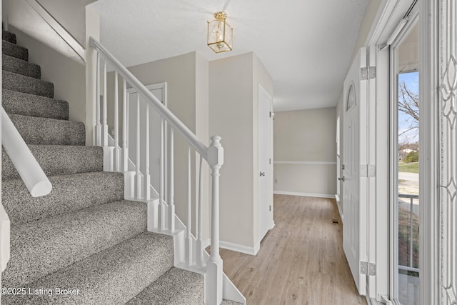 foyer featuring light wood finished floors, stairs, and baseboards