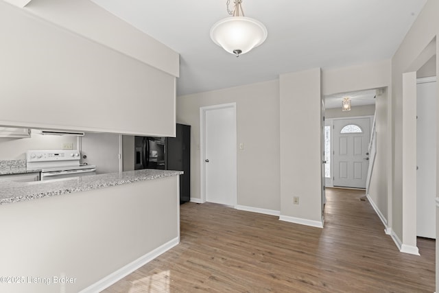 kitchen featuring electric stove, wood finished floors, baseboards, and light stone countertops