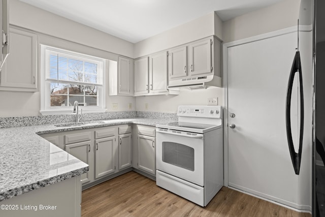 kitchen featuring under cabinet range hood, light wood-type flooring, light stone counters, white range with electric stovetop, and a sink