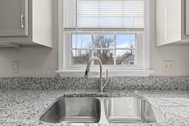 room details featuring a sink and light stone counters