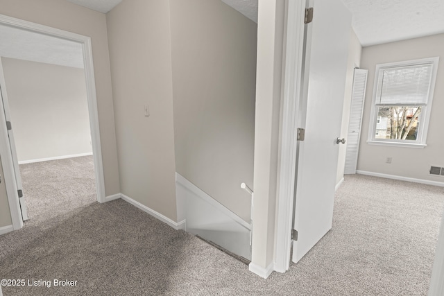 hall with baseboards, an upstairs landing, and carpet