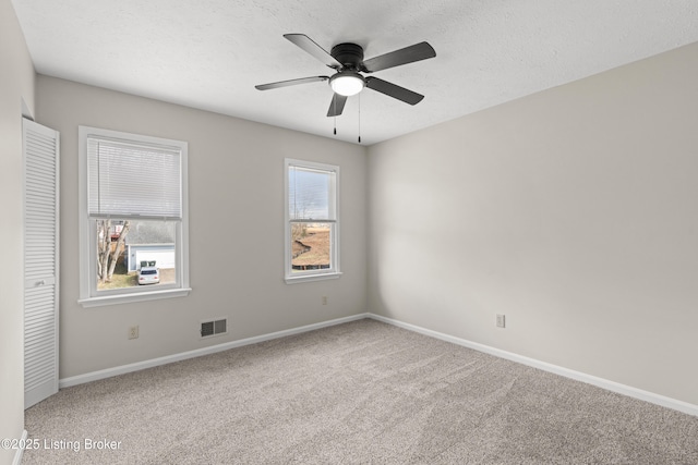 spare room featuring baseboards, visible vents, ceiling fan, a textured ceiling, and carpet flooring