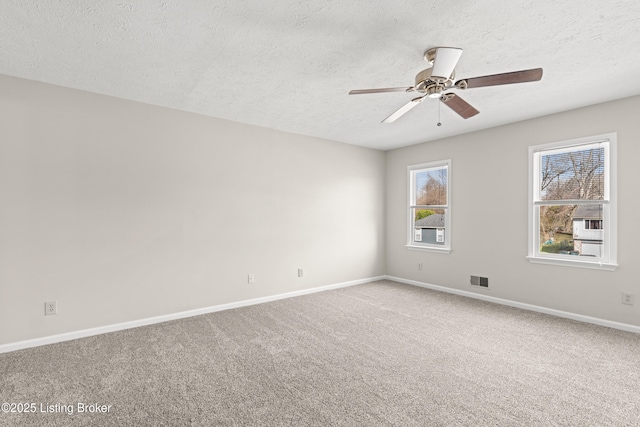 carpeted spare room featuring visible vents, baseboards, a textured ceiling, and ceiling fan