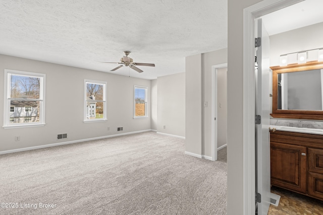 interior space with visible vents, a ceiling fan, baseboards, and a textured ceiling