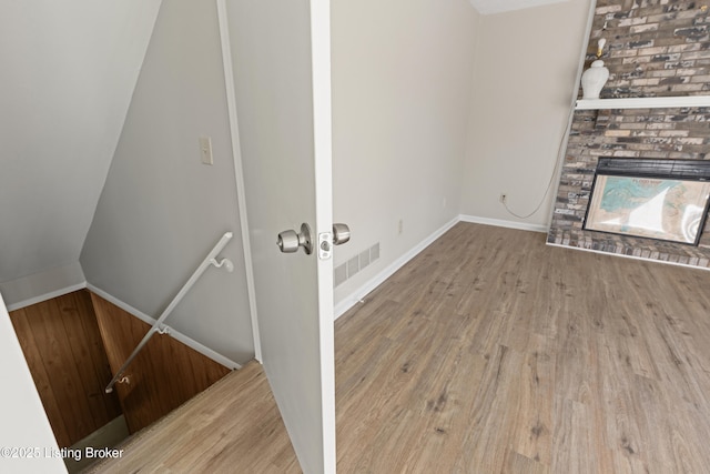 unfurnished living room featuring a multi sided fireplace, visible vents, and wood finished floors