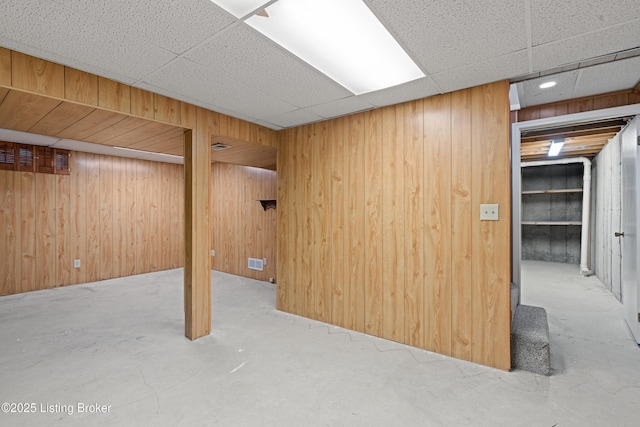 finished below grade area featuring wooden walls, a paneled ceiling, and visible vents