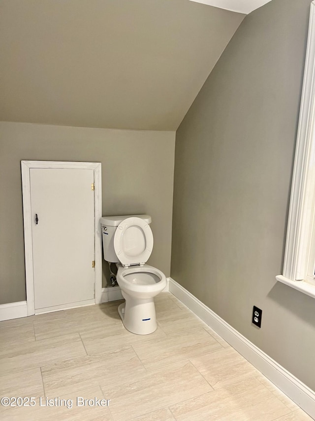 bathroom featuring lofted ceiling, toilet, and baseboards