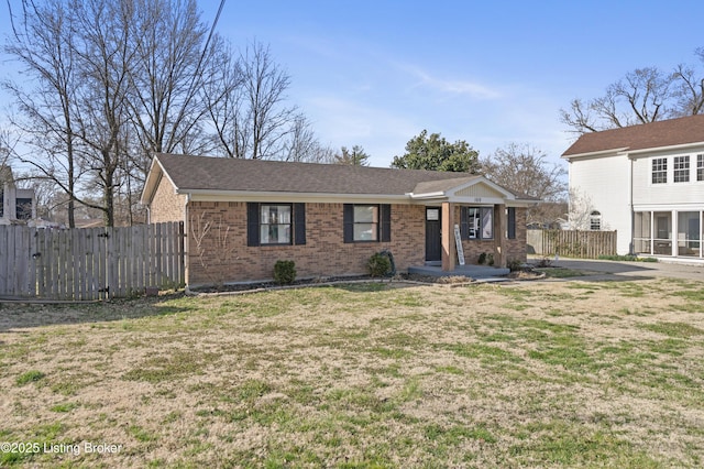 view of front of home with brick siding, a gate, a front yard, and fence
