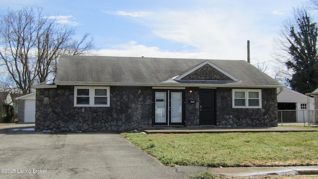 single story home featuring a front lawn, stone siding, and roof with shingles