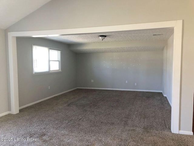 carpeted spare room featuring vaulted ceiling and baseboards