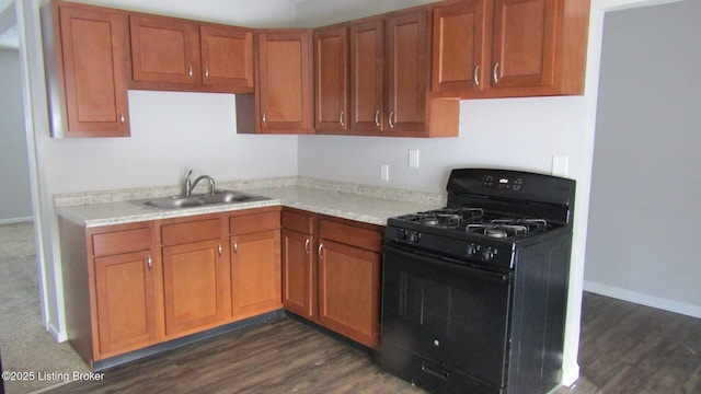 kitchen featuring a sink, black gas range oven, brown cabinetry, and light countertops