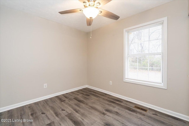 unfurnished room featuring dark wood-type flooring, baseboards, visible vents, and ceiling fan