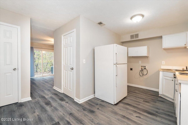 kitchen featuring dark wood-style floors, visible vents, white cabinetry, and freestanding refrigerator