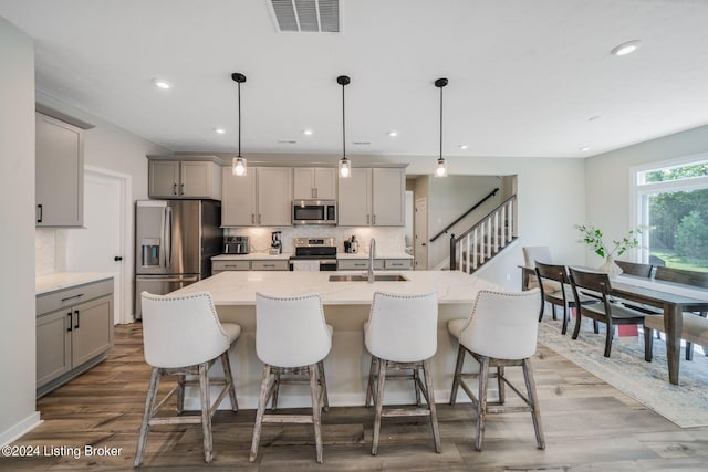 kitchen featuring wood finished floors, visible vents, a sink, gray cabinetry, and stainless steel appliances