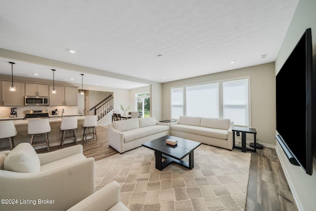 living area with stairs, recessed lighting, baseboards, and light wood-type flooring