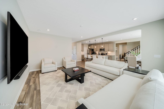 living room with stairway, light wood-style flooring, recessed lighting, and baseboards