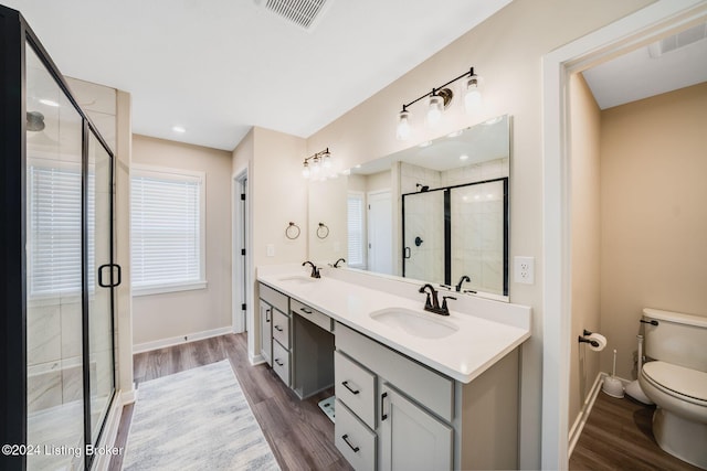 full bathroom with a stall shower, wood finished floors, visible vents, and a sink