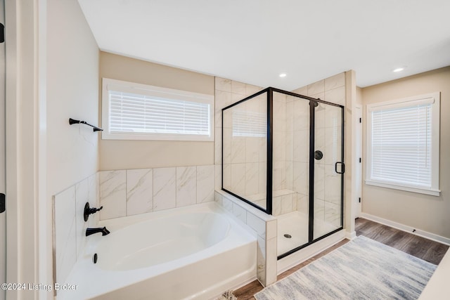 bathroom with a garden tub, a stall shower, wood finished floors, recessed lighting, and baseboards