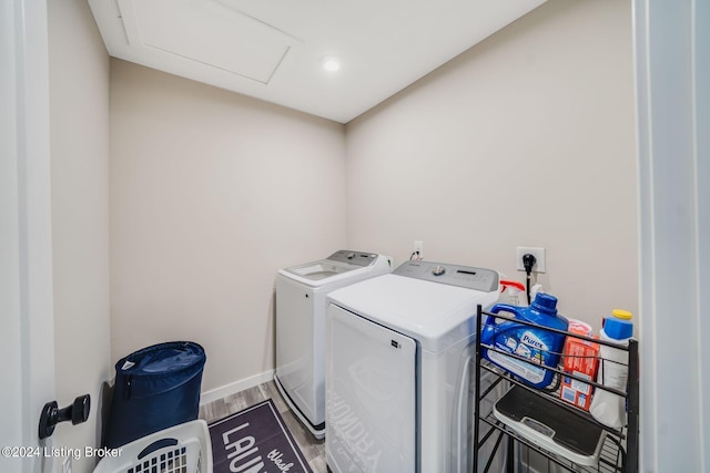 washroom with baseboards, attic access, laundry area, wood finished floors, and independent washer and dryer
