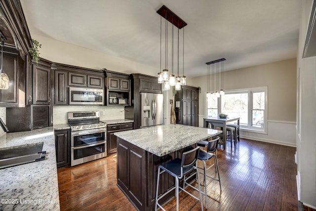 3140 Yorkshire Dr, Bardstown, KY 40004 - kitchen with a kitchen bar, stainless steel appliances, dark brown cabinets, decorative light fixtures, and dark wood-style floors
