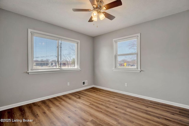 unfurnished room with visible vents, ceiling fan, baseboards, and wood finished floors