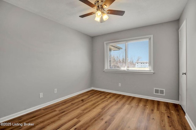 unfurnished room with visible vents, baseboards, wood finished floors, and a ceiling fan