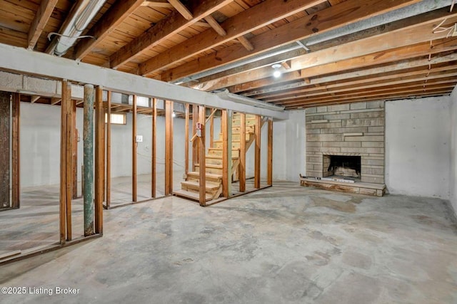 unfinished basement with a stone fireplace and stairs
