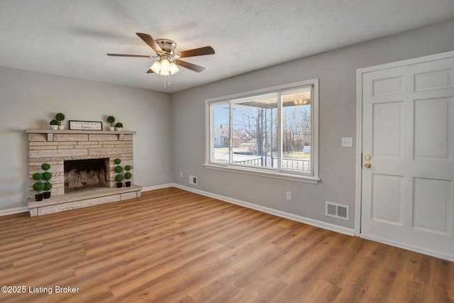 unfurnished living room with visible vents, baseboards, wood finished floors, and a ceiling fan