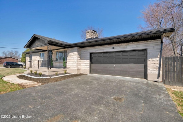 single story home featuring driveway, a porch, a chimney, stone siding, and a garage