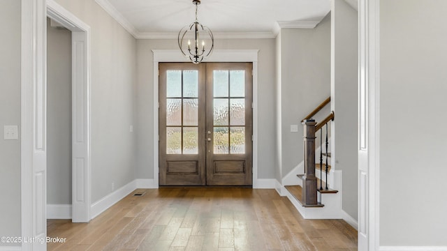 foyer entrance featuring wood finished floors, a notable chandelier, french doors, and ornamental molding