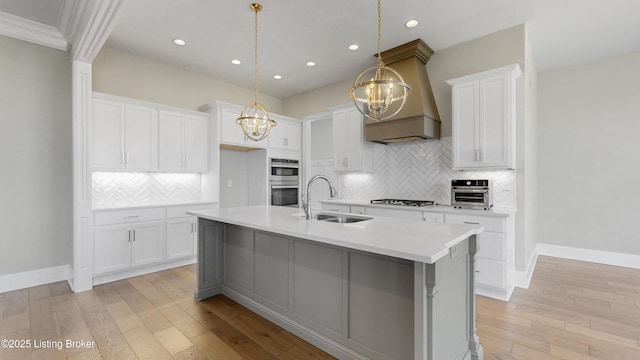 kitchen featuring a notable chandelier, a sink, light wood finished floors, custom exhaust hood, and light countertops