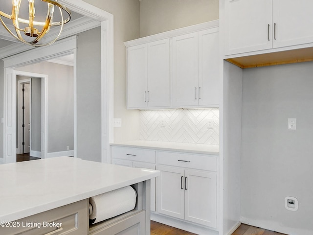 kitchen with tasteful backsplash, a chandelier, light countertops, hanging light fixtures, and white cabinetry