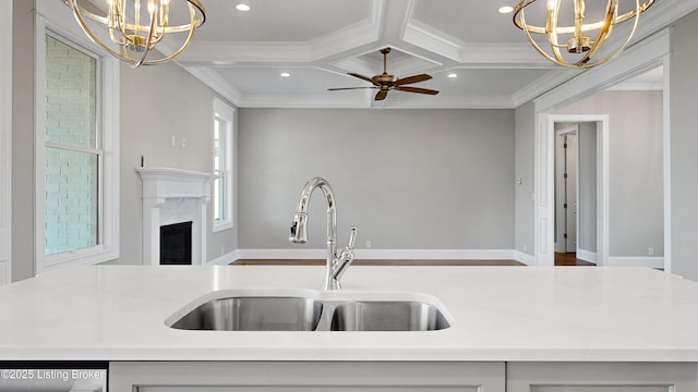 kitchen with coffered ceiling, crown molding, an inviting chandelier, and a sink