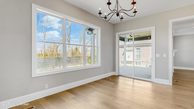 unfurnished dining area with an inviting chandelier, wood finished floors, baseboards, and visible vents