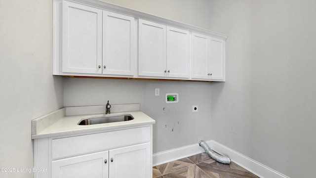 clothes washing area with baseboards, hookup for an electric dryer, cabinet space, a sink, and washer hookup