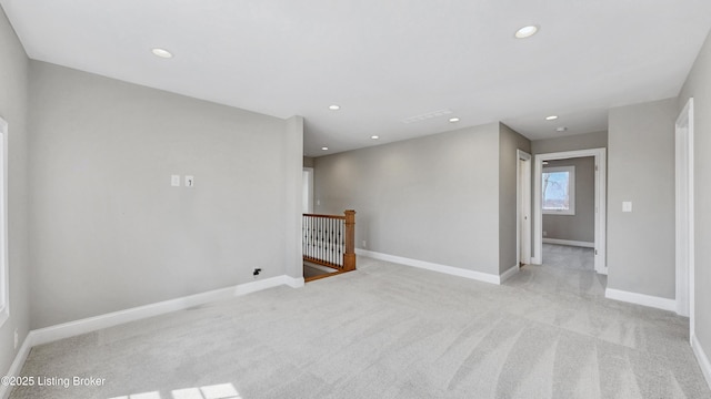 spare room featuring light carpet, recessed lighting, and baseboards