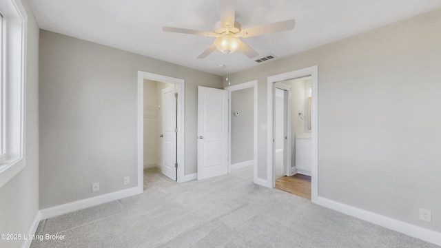 unfurnished bedroom featuring visible vents, a walk in closet, baseboards, and carpet floors