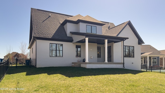 back of house featuring brick siding, a lawn, a shingled roof, and a fenced backyard