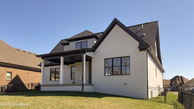 back of house with brick siding, a fenced backyard, a shingled roof, and a yard