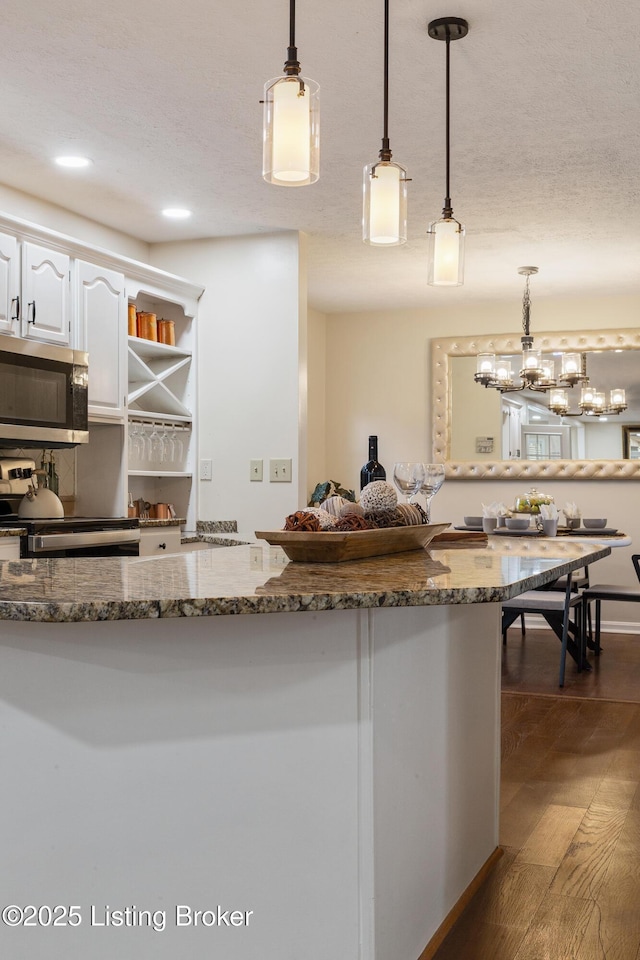 4316 Arwine Ct, Louisville, KY 40245 - kitchen with stainless steel microwave, dark wood finished floors, dark stone countertops, white cabinets, and range