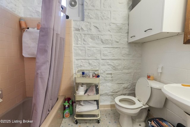 full bath with tile patterned flooring, shower / bath combination with curtain, toilet, and tile walls