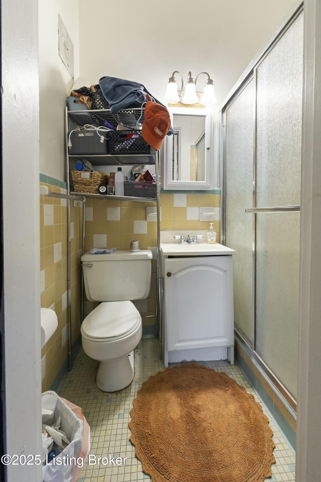 bathroom with vanity, a stall shower, tile patterned flooring, tile walls, and toilet