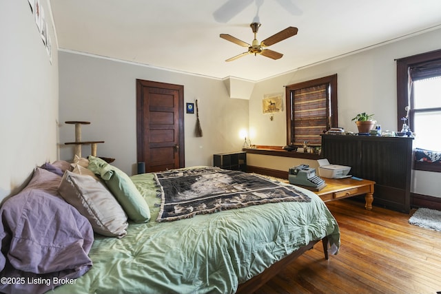 bedroom with a ceiling fan, hardwood / wood-style flooring, and crown molding