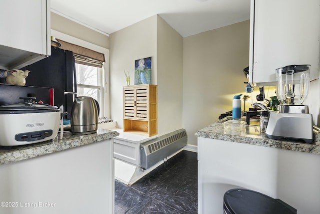 kitchen with water heater, freestanding refrigerator, white cabinets, light countertops, and baseboards
