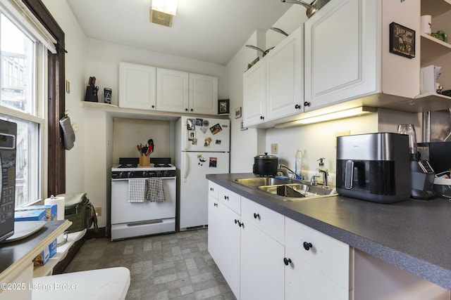kitchen featuring white appliances, open shelves, a sink, white cabinets, and dark countertops