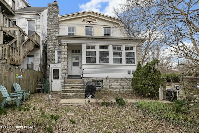 view of front facade with fence, a chimney, and entry steps